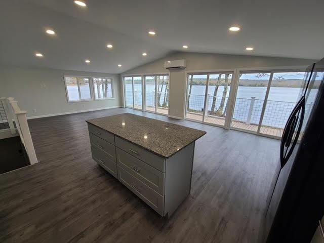 5 N Vigue Shore Rd, Albion, ME 04910 - kitchen featuring lofted ceiling, dark wood-type flooring, open floor plan, an AC wall unit, and a kitchen island