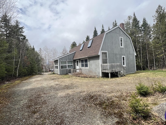 640 Bald Mountain Rd, Rangeley, ME 04970 - view of front of house with a gambrel roof, a chimney, a shingled roof, and a wooded view