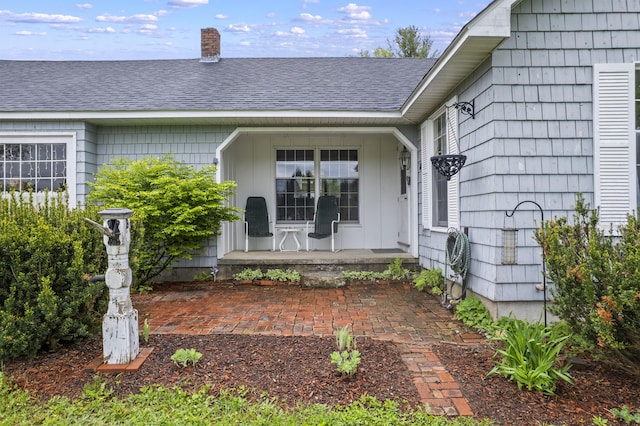 14 Lakeshore Dr, Belgrade, ME 04918 - doorway to property featuring covered porch, a chimney, and a shingled roof