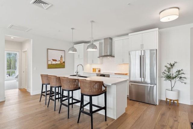 267 US Route 1 Unit 206, Falmouth, ME 04105 - kitchen with freestanding refrigerator, wall chimney exhaust hood, a sink, tasteful backsplash, and a breakfast bar