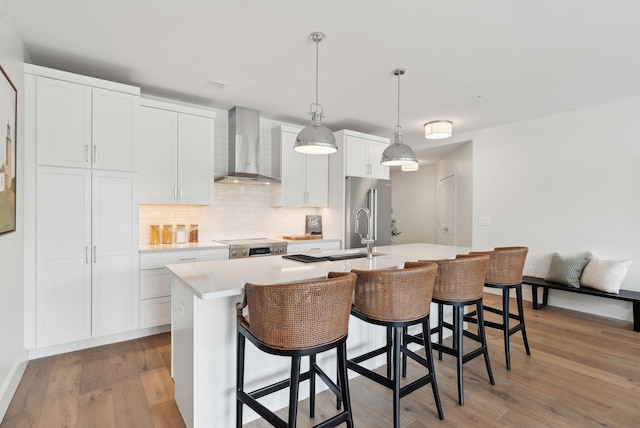 267 US Route 1 Unit 206, Falmouth, ME 04105 - kitchen with wall chimney range hood, an island with sink, light countertops, light wood finished floors, and white cabinetry