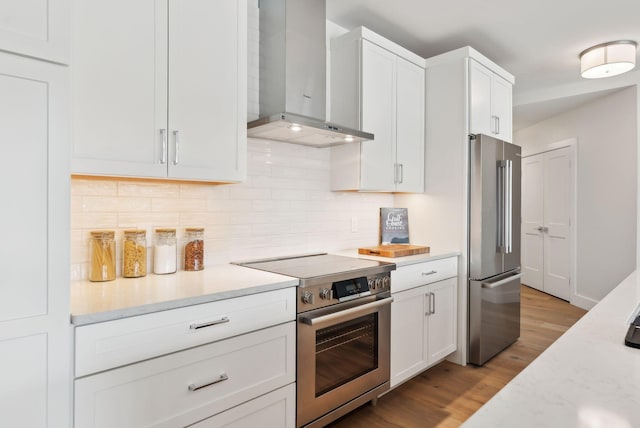 267 US Route 1 Unit 206, Falmouth, ME 04105 - kitchen featuring wall chimney exhaust hood, appliances with stainless steel finishes, backsplash, wood finished floors, and white cabinetry