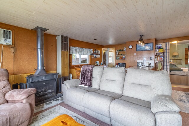 18 Breezy Knoll Dr, Princeton, ME 04668 - living room featuring wood walls, a wood stove, wooden ceiling, carpet floors, and a wall mounted AC