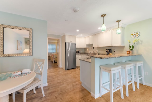 444 Main St Unit 110, Ogunquit, ME 03907 - kitchen with stainless steel appliances, a peninsula, stone counters, white cabinetry, and recessed lighting