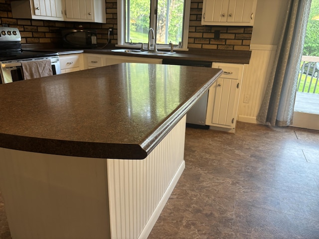 270 Mccrillis Corner Rd, Wilton, ME 04294 - kitchen featuring appliances with stainless steel finishes, dark countertops, decorative backsplash, white cabinets, and a kitchen island