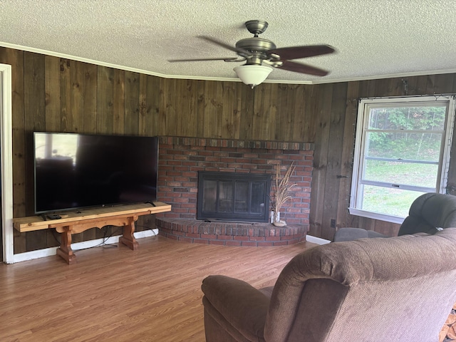 270 Mccrillis Corner Rd, Wilton, ME 04294 - living room featuring a textured ceiling, wood walls, a brick fireplace, wood finished floors, and ornamental molding