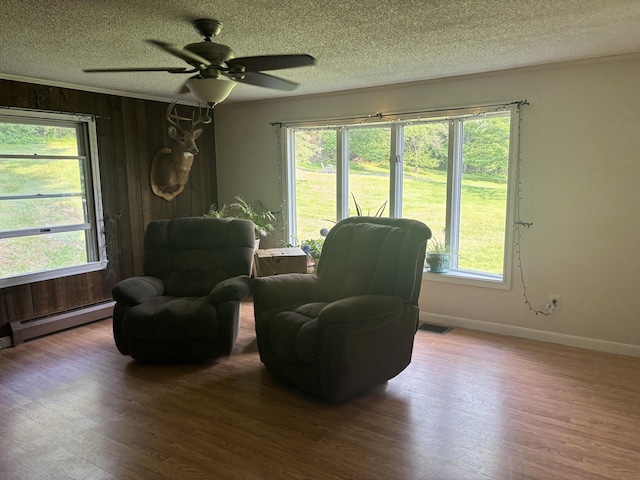 270 Mccrillis Corner Rd, Wilton, ME 04294 - sitting room with a textured ceiling, wood finished floors, a baseboard radiator, a ceiling fan, and wood walls