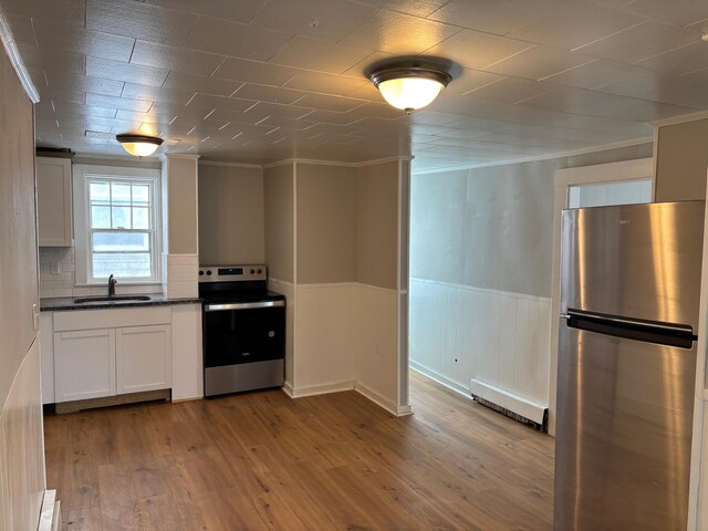 39 Foss St, Biddeford, ME 04005 - kitchen featuring stainless steel appliances, a baseboard radiator, a sink, dark countertops, and wainscoting