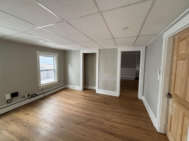 39 Foss St, Biddeford, ME 04005 - unfurnished bedroom featuring a baseboard heating unit, wood finished floors, a paneled ceiling, baseboards, and baseboard heating