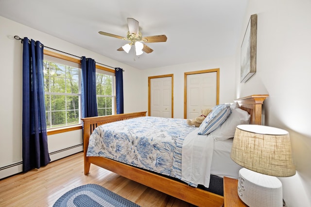 30 Maxfield Dr, Orono, ME 04473 - bedroom featuring wood finished floors, multiple closets, a baseboard heating unit, and a ceiling fan