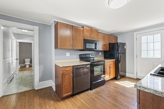 130 W Broadway, Bangor, ME 04401 - kitchen with black appliances, brown cabinets, baseboard heating, light wood-style floors, and crown molding