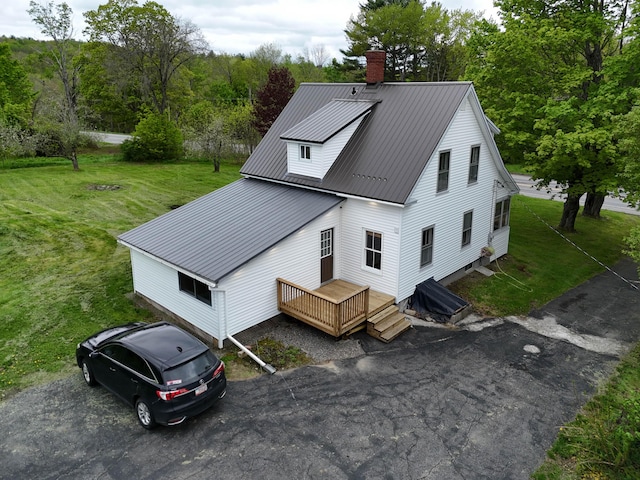 90 W Main St, Milo, ME 04463 - view of front of house featuring a chimney, a front lawn, metal roof, and a wooden deck
