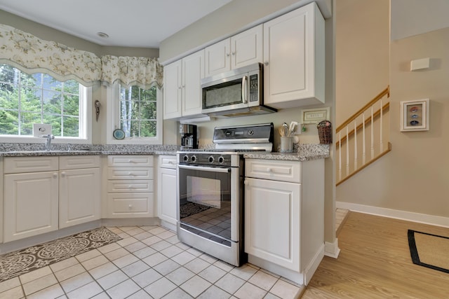 2 Round Cove Ln Unit 2, Phippsburg, ME 04562 - kitchen with gas stove, stainless steel microwave, white cabinetry, light stone countertops, and a sink