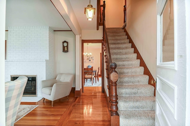 17 Bank Rd, York, ME 03909 - stairs featuring wood finished floors, a chandelier, and a brick fireplace