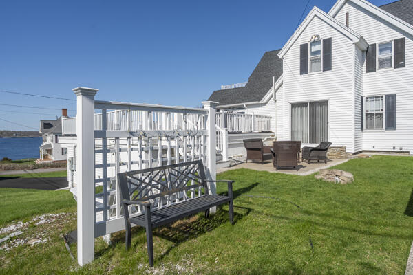 17 Bank Rd, York, ME 03909 - rear view of house featuring a yard, a patio, roof with shingles, and a wooden deck