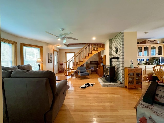 224 E Waterman Rd, Auburn, ME 04210 - living area featuring a wood stove, stairs, light wood-style floors, and ceiling fan