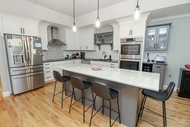 9 Camden Ct Unit 9, Bangor, ME 04401 - kitchen with appliances with stainless steel finishes, wall chimney range hood, a sink, and a kitchen bar