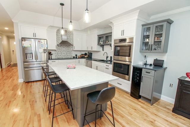 9 Camden Ct Unit 9, Bangor, ME 04401 - kitchen featuring appliances with stainless steel finishes, beverage cooler, wall chimney exhaust hood, a breakfast bar, and decorative backsplash