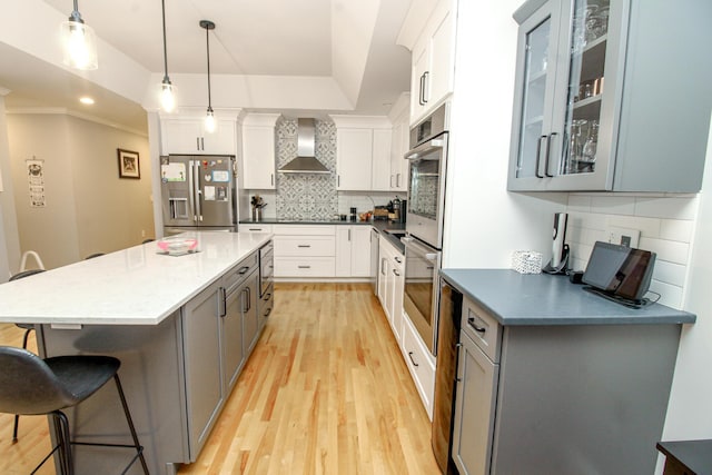 9 Camden Ct Unit 9, Bangor, ME 04401 - kitchen with stainless steel appliances, wall chimney exhaust hood, a breakfast bar area, light wood-style floors, and tasteful backsplash
