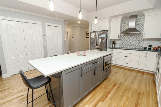 9 Camden Ct Unit 9, Bangor, ME 04401 - kitchen featuring wall chimney range hood, appliances with stainless steel finishes, tasteful backsplash, white cabinetry, and crown molding