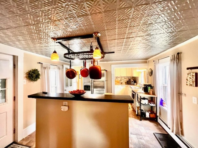 90 N Ave, Skowhegan, ME 04976 - kitchen with stainless steel refrigerator with ice dispenser, a kitchen island, dark countertops, baseboard heating, and an ornate ceiling