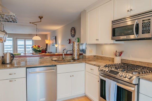 311 Chandlers Wharf Unit 311, Portland, ME 04101 - kitchen with stainless steel appliances, a sink, light stone countertops, and white cabinetry