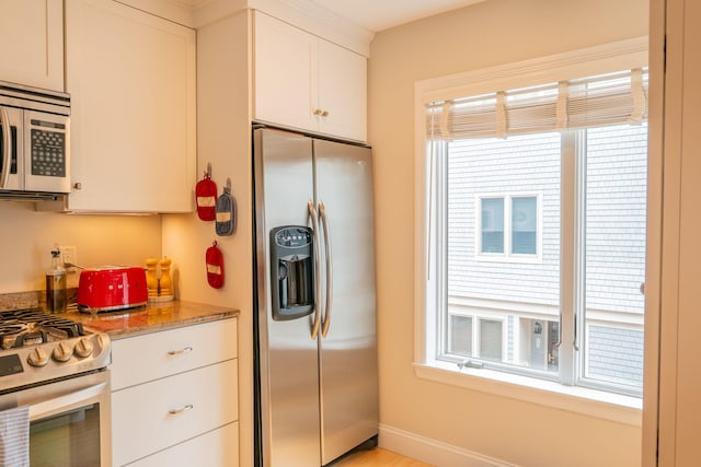 311 Chandlers Wharf Unit 311, Portland, ME 04101 - kitchen with stainless steel appliances, white cabinetry, and light stone countertops