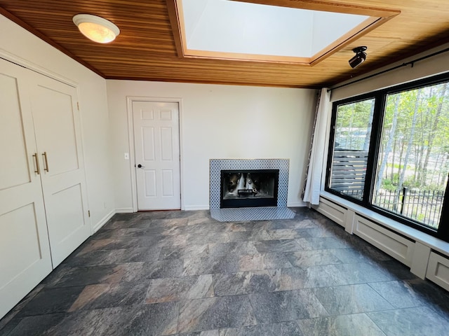 341 Ellsworth Rd, Blue Hill, ME 04614 - unfurnished living room with wooden ceiling, dark stone finish floors, a tiled fireplace, and baseboards