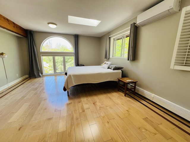 341 Ellsworth Rd, Blue Hill, ME 04614 - bedroom with a wall unit AC, light wood-style floors, a skylight, and baseboards