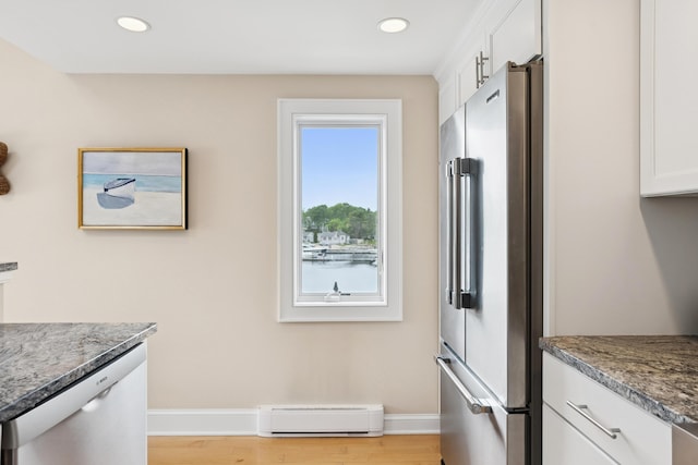 47 Ocean Ave Unit 6, Kennebunkport, ME 04046 - kitchen with appliances with stainless steel finishes, baseboard heating, white cabinets, light wood-style flooring, and stone countertops