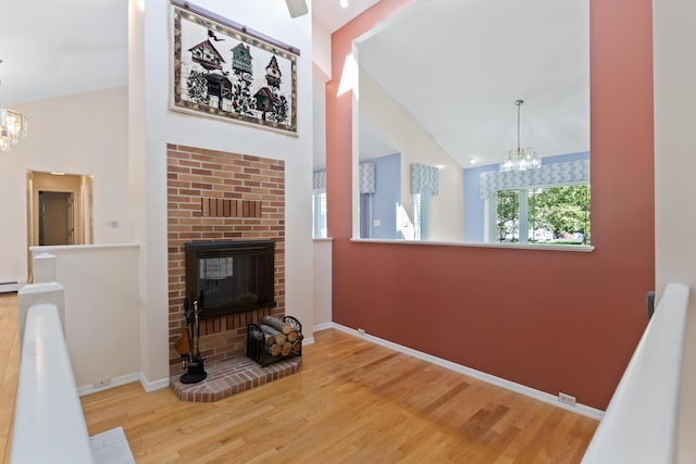 37 Longbow Ct, Auburn, ME 04210 - living room featuring a chandelier, wood finished floors, a brick fireplace, baseboards, and high vaulted ceiling