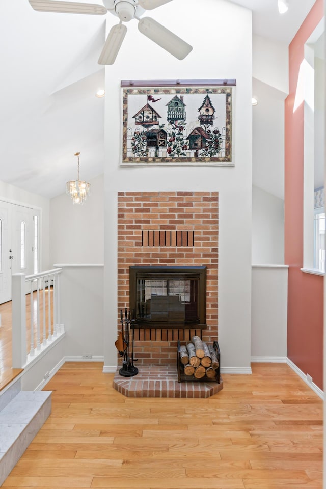 37 Longbow Ct, Auburn, ME 04210 - unfurnished living room featuring wood finished floors, baseboards, ceiling fan, a brick fireplace, and a chandelier