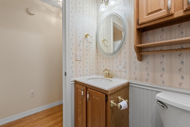 37 Longbow Ct, Auburn, ME 04210 - half bathroom with vanity, toilet, wallpapered walls, wood finished floors, and baseboards