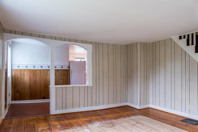 57 Bow St, Freeport, ME 04032 - unfurnished room featuring hardwood / wood-style floors, wooden walls, and stairs