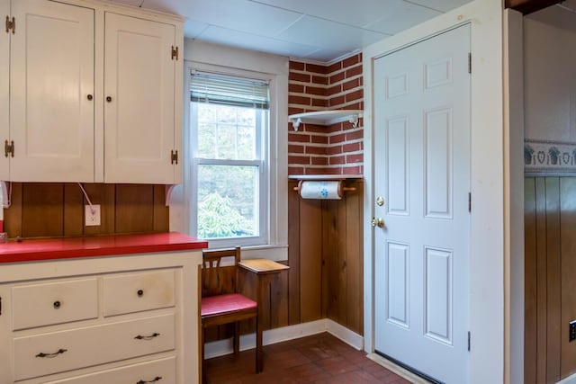 57 Bow St, Freeport, ME 04032 - kitchen with healthy amount of natural light, white cabinets, light countertops, wood walls, and baseboards