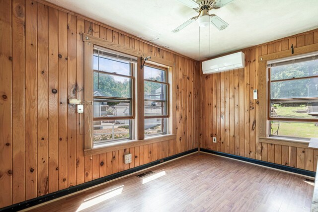 27 Maple St, Limerick, ME 04048 - empty room featuring an AC wall unit, wood finished floors, baseboards, a ceiling fan, and wood walls