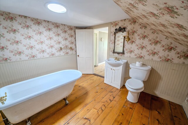 176 Bagley Hill Rd, Troy, ME 04987 - full bath featuring hardwood / wood-style flooring, a soaking tub, vanity, wainscoting, and toilet