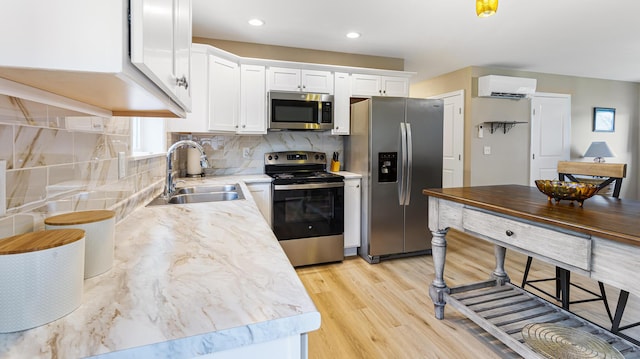 51 Stearns Farm Rd, Hampden, ME 04444 - kitchen with appliances with stainless steel finishes, a sink, a wall mounted AC, light wood-style flooring, and white cabinetry