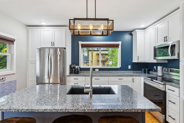 124 Dumont Ave, Lewiston, ME 04240 - kitchen with stainless steel appliances, a sink, a kitchen bar, white cabinetry, and stone counters
