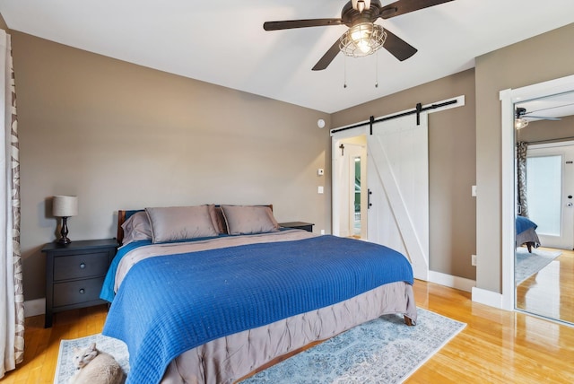 124 Dumont Ave, Lewiston, ME 04240 - bedroom featuring a barn door, wood finished floors, baseboards, and ceiling fan