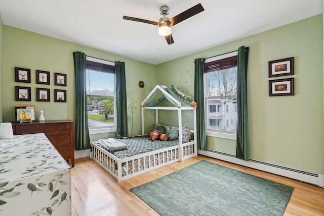 124 Dumont Ave, Lewiston, ME 04240 - bedroom with multiple windows, wood finished floors, and a baseboard radiator