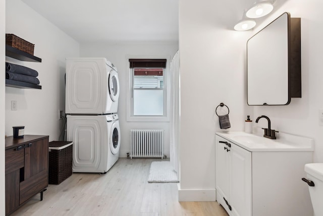 124 Dumont Ave, Lewiston, ME 04240 - laundry room with radiator heating unit, stacked washer / dryer, and light wood-style floors