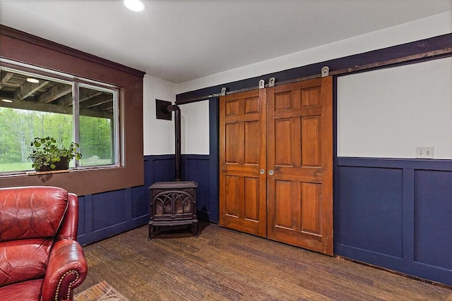 39 Lobo Ln, West Gardiner, ME 04345 - living area featuring a wood stove, wainscoting, a decorative wall, and dark wood-type flooring