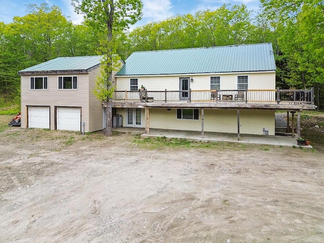 39 Lobo Ln, West Gardiner, ME 04345 - view of front of house featuring a deck, metal roof, an attached garage, and view of scattered trees