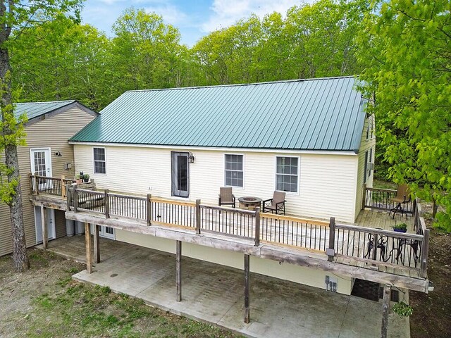 39 Lobo Ln, West Gardiner, ME 04345 - back of property with a wooden deck, metal roof, and a patio area