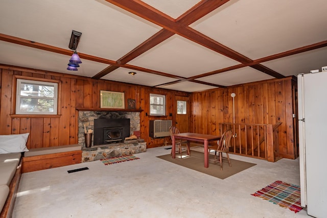 54 Papoose Island Rd, Raymond, ME 04071 - dining room with wooden walls, a wood stove, coffered ceiling, unfinished concrete flooring, and beamed ceiling
