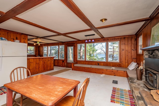 54 Papoose Island Rd, Raymond, ME 04071 - dining room with healthy amount of natural light, wooden walls, a wood stove, and beamed ceiling