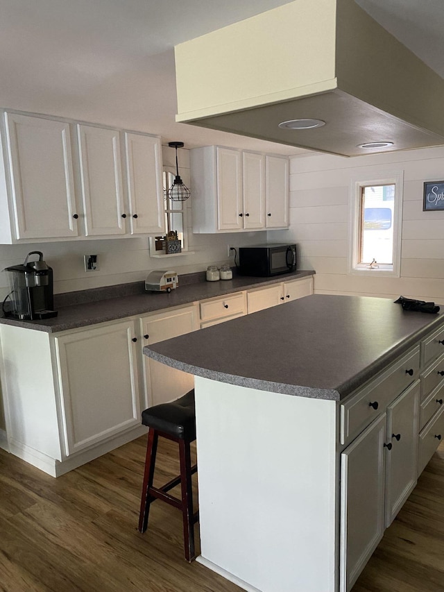 476 Springy Pond Rd, Otis, ME 04605 - kitchen featuring black microwave, dark countertops, dark wood-style flooring, white cabinetry, and a kitchen bar