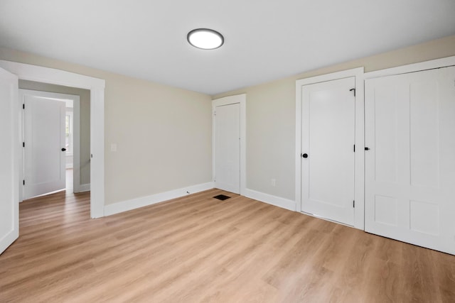 50 14th St, Bangor, ME 04401 - unfurnished bedroom with light wood-style floors, baseboards, and multiple closets