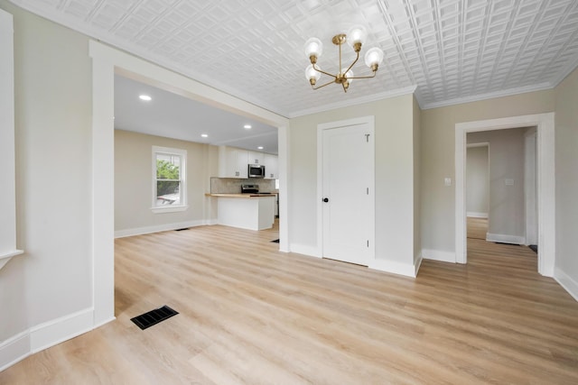 50 14th St, Bangor, ME 04401 - unfurnished living room featuring a chandelier, baseboards, light wood finished floors, an ornate ceiling, and ornamental molding